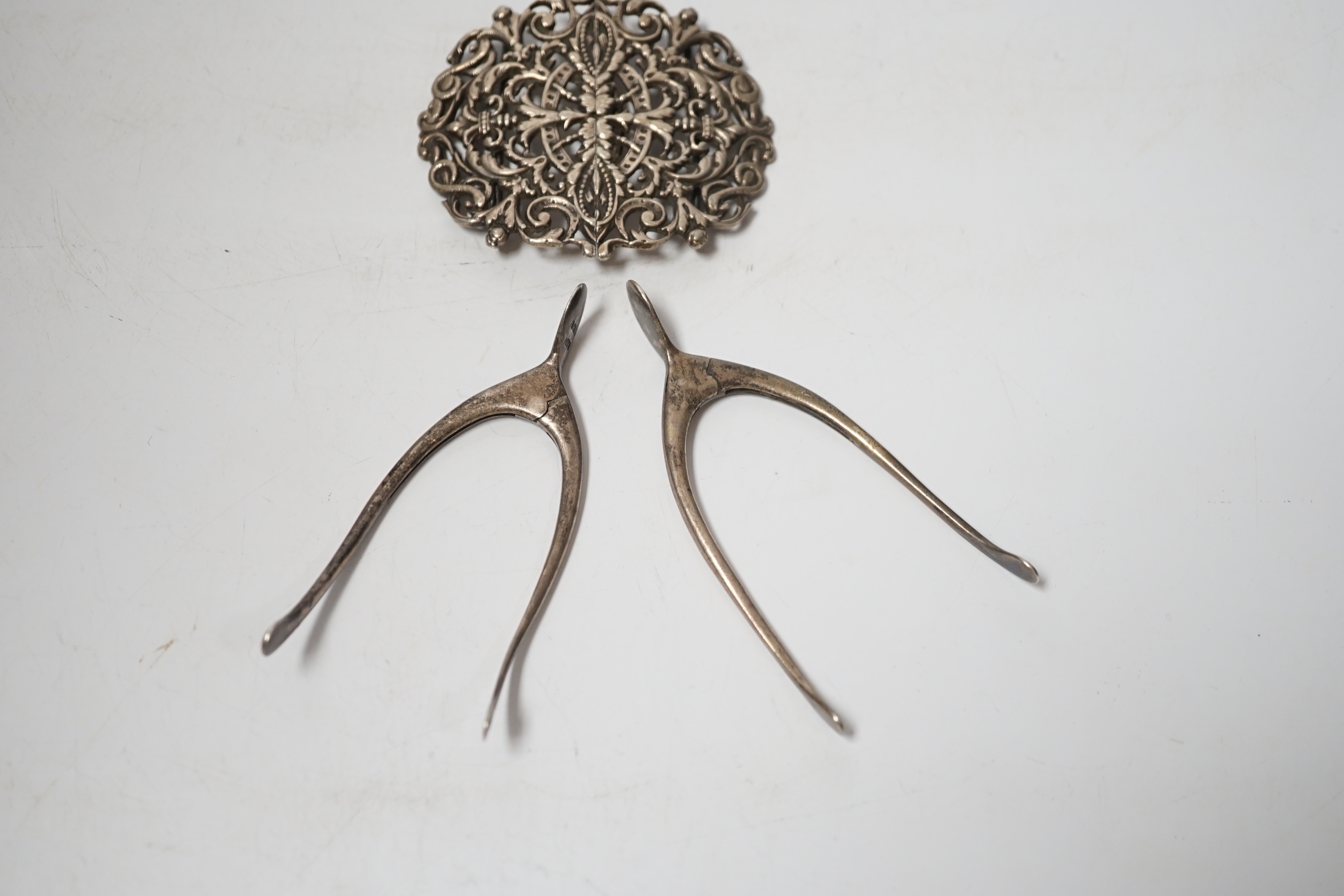 Two pairs of Edwardian silver wishbone shaped sugar nips, both by Levi & Salaman, Birmingham, 1903 and 1906, largest 85mm, together with a late Victorian pierced silver belt buckle, Birmingham, 1898.